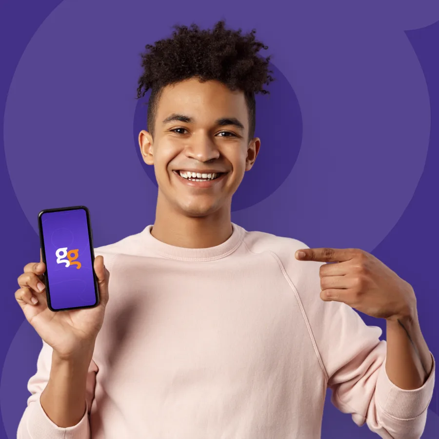 Jovem sorrindo aponta para o celular com o aplicativo da Diggi na tela